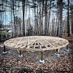 a circular wooden structure in the woods surrounded by trees