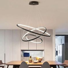 a modern chandelier hangs over a dining room table with chairs and a bowl on it