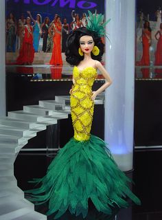 a barbie doll dressed in a yellow and green dress with feathers on it's tail