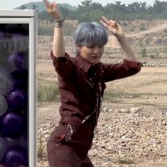 a man with blue hair is dancing in front of some purple and white balls on the ground