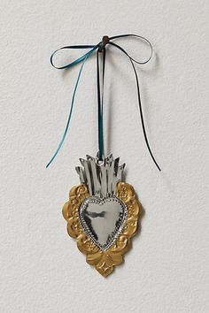 a heart shaped ornament hanging from a string on a white wall with a blue ribbon