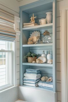 the shelves in this bathroom are filled with towels and seashells on top of them