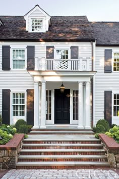 a white house with black shutters and steps leading up to the front door area