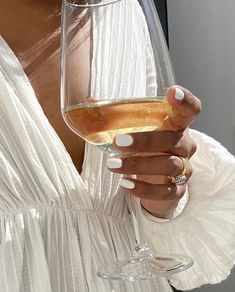 a woman holding a wine glass in her right hand and wearing a ring on her left finger