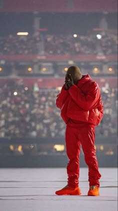 a man in red is talking on his cell phone while wearing an orange jacket and matching sneakers