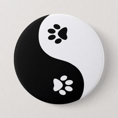 a black and white button with a dog paw on it's left side, in the shape of a yin symbol