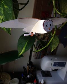 an owl ornament hanging from a tree branch with leaves and other items around it