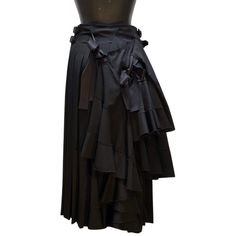 Introducing the TAO CDG Pleated Skirt. This magnificent black wool skirt wraps and fastens with attached buckles at the hips. The layered fabric and elegant satin bows in the back make this skirt a stylish and attractive addition to any wardrobe. The TAO CDG Pleated Skirt is available now at Anastasia Boutique. Style # 3SS010. Make a statement with this beautiful skirt and show off your fashion sense. Wool Wrap Skirt, Black Wool Skirt, Comme Des Garcons Black, Layered Fabric, Beautiful Skirt, Wool Wrap, Boutique Style, Wool Skirt, Beautiful Skirts