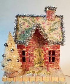 a small red house sitting on top of a table next to a white christmas tree