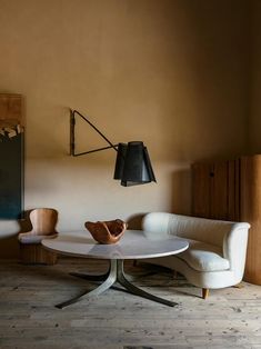 a living room with a white couch, table and lamp on the wall next to it