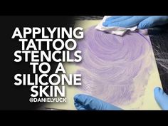 someone in blue gloves is applying tattoo stencils to a silcone skin