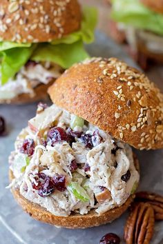 two chicken salad sandwiches with lettuce, cranberries and pecans on a plate