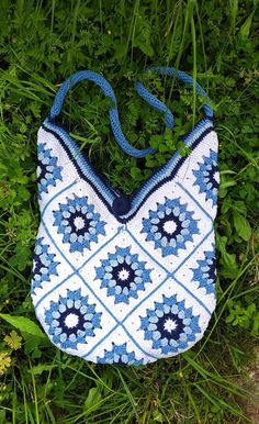 a blue and white purse laying on the grass