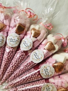 there are many pink candy sticks with gold foil hearts on them, all wrapped in cellophane