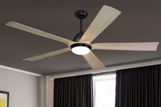 a ceiling fan in a room with curtains