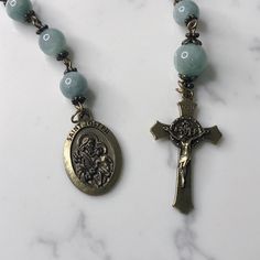 Handmade traditional Catholic single decade tenner rosary using green dyed jade smooth stone round beads. Antique bronze daisy bead caps on every bead with additional flower bead caps on Our Father bead. Antique bronze St. Joseph-Patron Saint of fathers, families and carpenters-Medal with Miraculous Medal Crucifix. Hail Mary beads are 8mm with the Our Father bead being 10mm. Designed to be used and/or displayed. Measures about 10" long. This rosary would make a beautiful gift for a baby shower, Baptism, First Communion, Confirmation, Father's Day, or any other special event or occasion. Comes in a beautiful black velvet pouch. I ship same or next business day. All of my rosaries are one of a kind and are my own personal creation. Photos are a part of the description-you will receive the ex Pocket Rosary, Our Father, Hail Mary, Miraculous Medal, Velvet Pouch, Patron Saints, St Joseph, Green Jade, Bead Caps