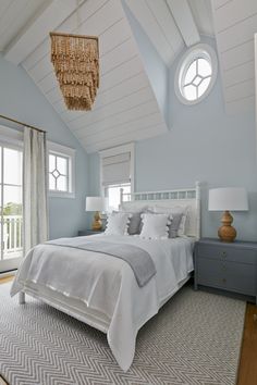 a bedroom with blue walls and white bedding in the center is an image of a chandelier hanging from the ceiling