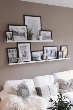 a living room filled with white furniture and pictures on the wall above it's headboard