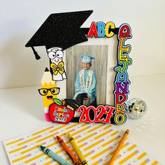 a graduation photo frame with crayons and pencils next to it