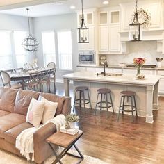 the kitchen cabinets are white and there is a brown couch in front of the kitchen island