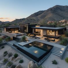 an aerial view of a modern home in the desert at dusk with mountains in the background