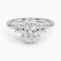 an oval cut diamond ring with three smaller diamonds on the band, set in 18k white gold