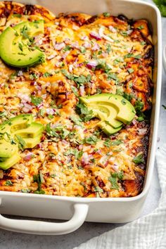 an enchilada casserole with sliced avocados and cilantro