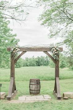 an outdoor ceremony with a barrel and flowers