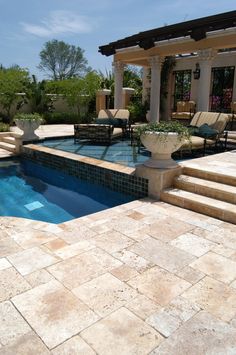 an outdoor swimming pool with steps leading up to it and a covered patio area in the background