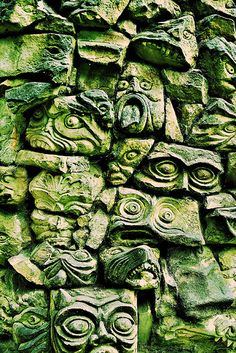 an image of some kind of art work on the side of a stone wall with many faces