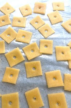 several square pieces of cheese are on a sheet of wax paper with holes in the middle