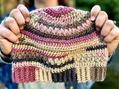 a person holding up a multicolored knitted hat in front of their face