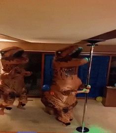 two inflatable dinosaurs are dancing on the dance floor with their arms outstretched