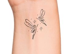 a woman's arm with a small tattoo of two dragonflys on it