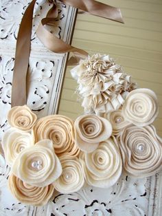 a bunch of fabric flowers are hanging on a door hanger with a brown ribbon