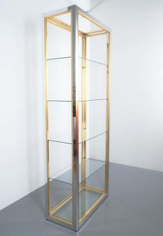 a tall glass display case sitting on top of a gray floor next to a white wall