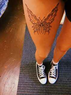 a woman's legs with a butterfly tattoo on her lower leg and white tennis shoes