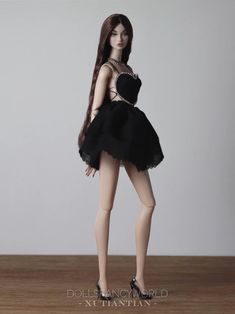 a doll with long hair wearing a black dress and high heeled shoes is posed on a wooden table