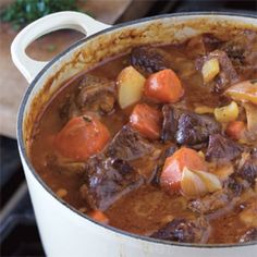 a pot filled with stew and carrots on top of a stove