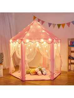 a pink play tent with fairy lights and stuffed animals on the floor next to it