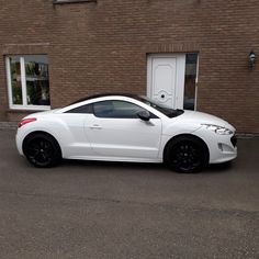 a white sports car parked in front of a brick building