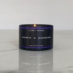 a candle sitting on top of a table next to a white marble counter with the words scorpion and geranium written across it