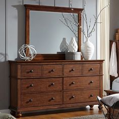 a wooden dresser sitting next to a window with a mirror on it's side