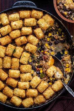 a skillet filled with tater tots and beans next to a bowl of cornbreads