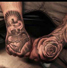 two mens hands with tattoos on them holding roses and a cross in the middle