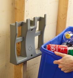 a person holding a can in their hand next to a blue bin