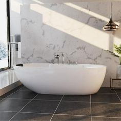 a large white bath tub sitting in a bathroom next to a window and potted plant