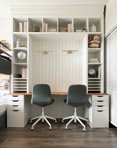 two office chairs sitting in front of a desk with bookshelves and shelves on the wall