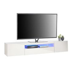 a flat screen tv sitting on top of a white entertainment center next to a potted plant