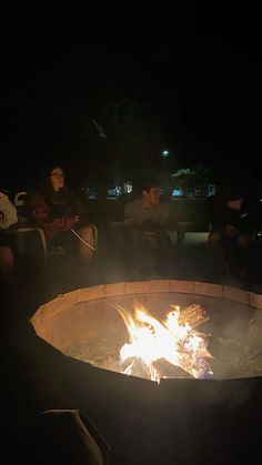 people sitting around a fire pit at night